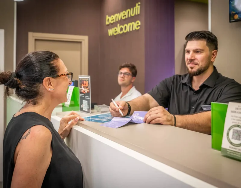 Receptionist accoglie cliente al banco dell'hotel.