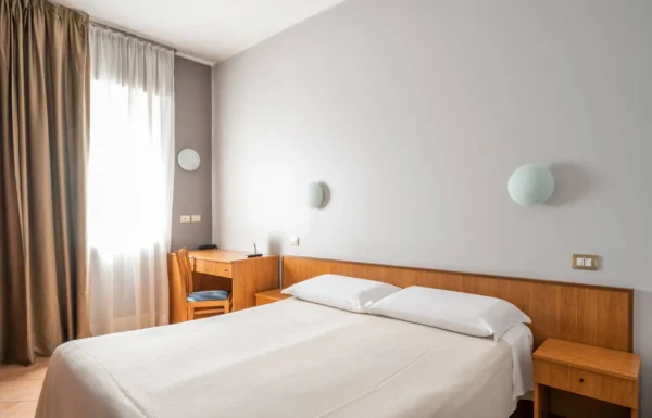 Camera da letto semplice con letto matrimoniale e scrivania.