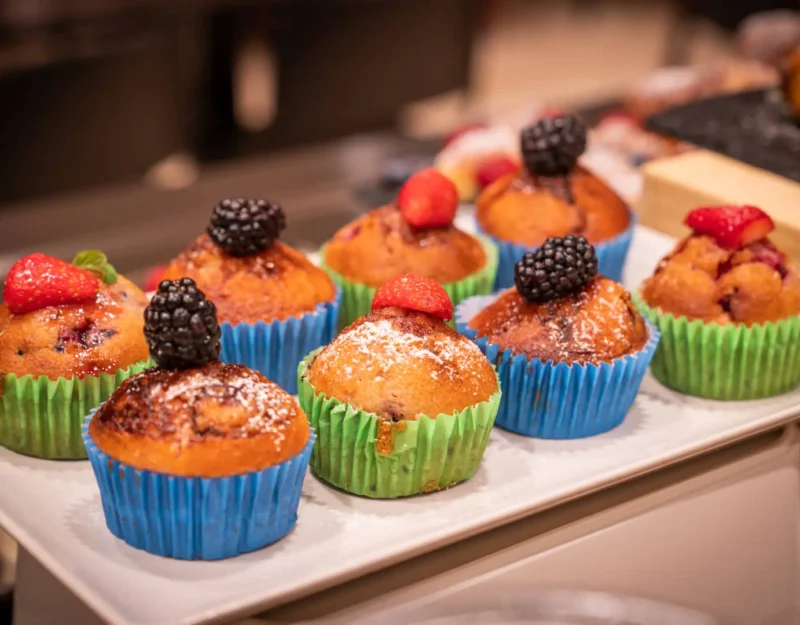 Muffin decorati con frutti di bosco su vassoio bianco.