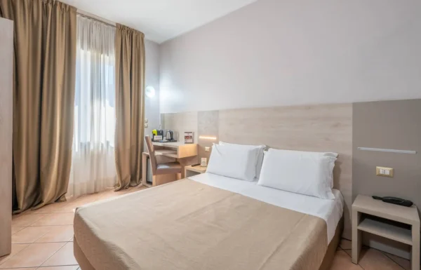 Camera d'albergo luminosa con letto matrimoniale.