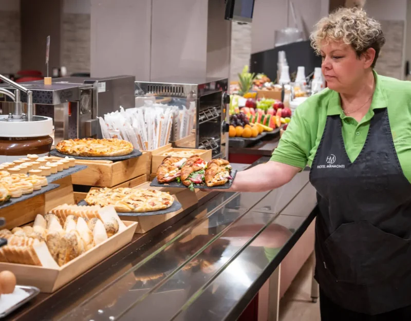 Personale prepara buffet con assortimento di cibo e bevande.